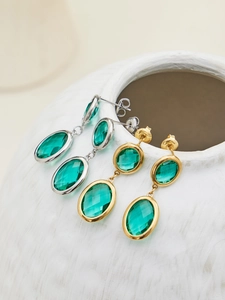 Detail of elegant gold and silver earrings with double green oval faceted glass stones