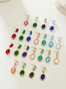 Macro shot of colorful oval glass earrings in various gemstone colors on white background