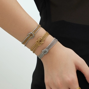 Tre bracciali a nodo in acciaio inossidabile nei colori oro e argento al polso