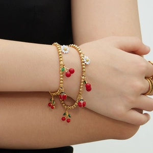 Bracelets en perles dorées avec breloques émaillées cerise, marguerite et coccinelle