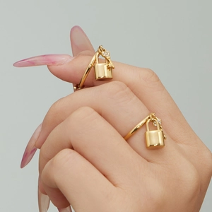 Micro-paved zircon lock pendant gold rings on finger for a minimalist layered look