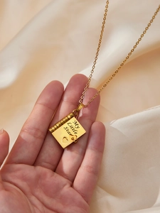 Dettaglio della collana medaglione a libro in oro con incisione su raso lucido