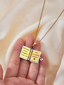 Dettaglio macro della collana a libro apribile con incisione e cuore per la figlia