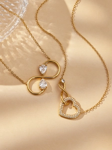 Détail de colliers dorés avec symbole infini et pendentif cœur serti de zircons