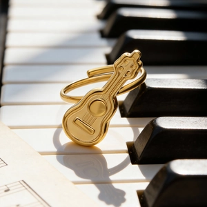 Goldener offener Gitarrenring aus Edelstahl, präsentiert auf Klaviertasten