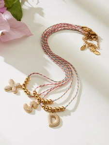Detailed view of woven colorful rope necklaces with gold zircon letter pendants X, S, and D
