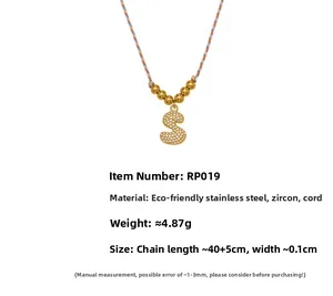 Detailed view of gold letter S pendant with pavé zircons and colorful braided rope chain