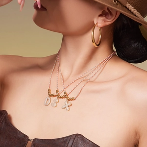 Rainbow cord necklaces with iced-out alphabet pendants and large gold hoop earrings