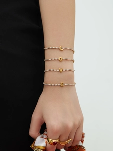 Detail of four gold tennis bracelets with LOVE letters and zircon on model's wrist