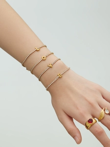 Detail of model wearing 18k gold-plated tennis bracelets forming LOVE with zircon letters
