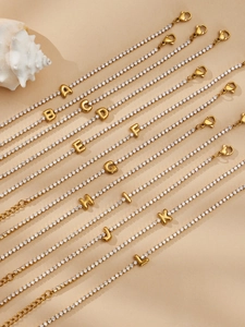 Macro detail of 18k gold plated tennis bracelets with sparkling zircon initial pendants