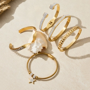 Ensemble de bracelets géométriques dorés et chaîne de cheville étoile sur décor de sable