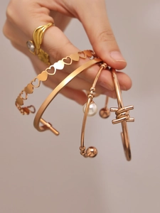 Detail of 18k gold plated stainless steel bangles with heart motifs and pearls on wrist