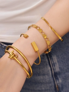 Close-up of four-piece gold plated stainless steel heart and geometric bracelet set on wrist