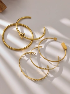 Macro detail of a 5-piece 18k gold-plated bangle set featuring minimalist heart patterns