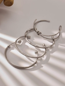 Detail of four silver stainless steel bracelets with knot and textured mesh designs