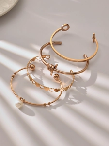 Detail of 4-piece rose gold bangle set featuring interlocking hearts and pearl charm