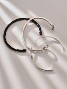 Close-up of minimalist stainless steel open bangles with unique textures and shadow