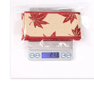 Detail view of maple leaf pattern ribbon on a digital scale showing weight of 21.3 grams