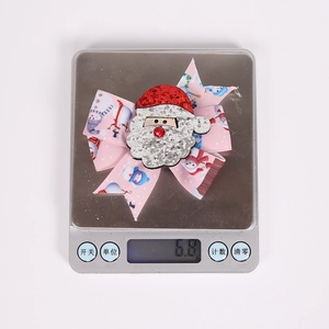 Close-up of a pink snowman bow hair clip weighing 6.8g on a digital scale for kids