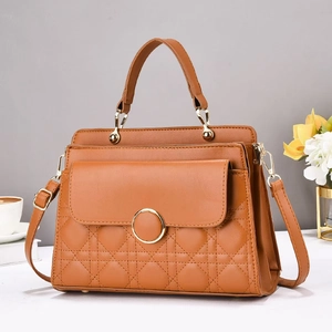 Detail view of the quilted stitching and golden metal buckle on the caramel leather handbag