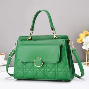 Detail showing emerald green quilted handbag with gold hardware and classic texture