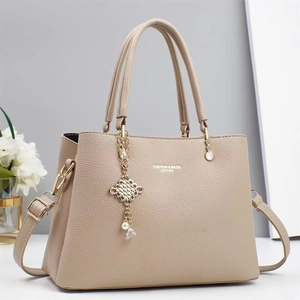 Minimalist beige pebble leather handbag with gold chain and pearl charm detail