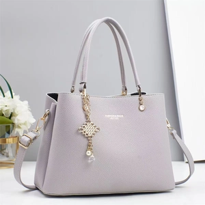 Detail of lavender litchi pattern handbag with gold hardware and tassel charm