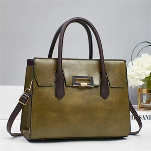Detail of dark green vintage tote bag featuring dark brown handles and golden buckle hardware