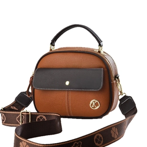 Brown pebbled leather crossbody bag with floral strap and gold logo on white background