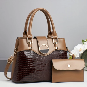 Close-up of brown crocodile embossed handbag set with golden hardware and small wallet