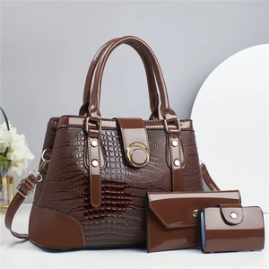 Vue détaillée de la texture lézard marron foncé et boucle dorée sur les sacs à main de luxe