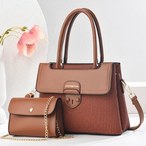 Close-up of brown textured leather handbag set with gold chain and brand logo details