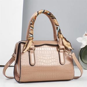 Detail of stone embossed leather handbag featuring silk scarf wrapped handles and gold hardware