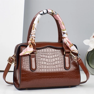 Detail of dark brown faux crocodile leather handbag with silk scarf wrapped handle