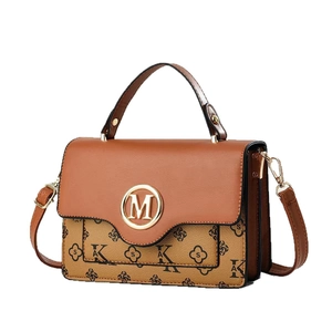 Elegante bolso de mano bicolor con logo M dorado y patrón de monogramas en vista de 45 grados