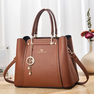 Détail d'un sac à main marron foncé en cuir grainé avec logo kangourou doré et pendentif étoile