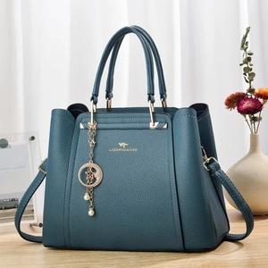 Détail du sac cabas en cuir grainé bleu canard avec logo doré et breloque perle