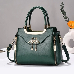 Sac à main vintage vert foncé avec décor de cygne et pompon perlé sur table blanche