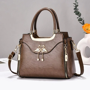 Détail d'un sac marron avec boucle cygne dorée et pompon perlé élégant