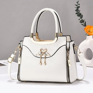 Sac à main blanc avec logo cygne doré et pendentifs en perles sur décor minimaliste