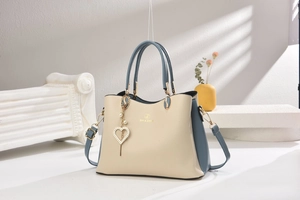 Détail du sac à main bicolore avec ferrures dorées et pendentif en forme de cœur diamanté
