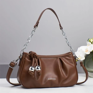 Detail of pleated brown leather cloud bag featuring silver chain strap and metal charms