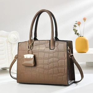 Detail of tan crocodile embossed texture on luxury handbag with gold hardware