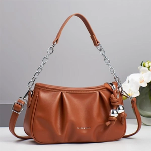 Detail of pleated brown handbag with fashion text and silver chain strap connector