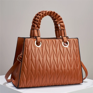 Détail du sac à main marron matelassé avec texture en losange et poignée tressée