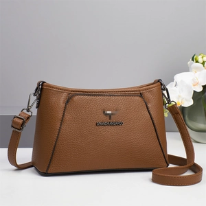 Close-up of litchi pattern leather texture and metal logo on brown shoulder bag