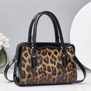 Detailed view of leopard print handbag featuring glossy finish and gold-tone metal hardware