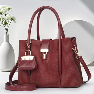 Detail of burgundy striped tote bag with wave texture, gold clasp, and mini charm