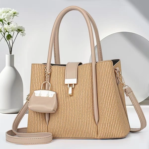 Elegant beige pleated tote bag with golden lock and miniature bag charm in high-end studio setting